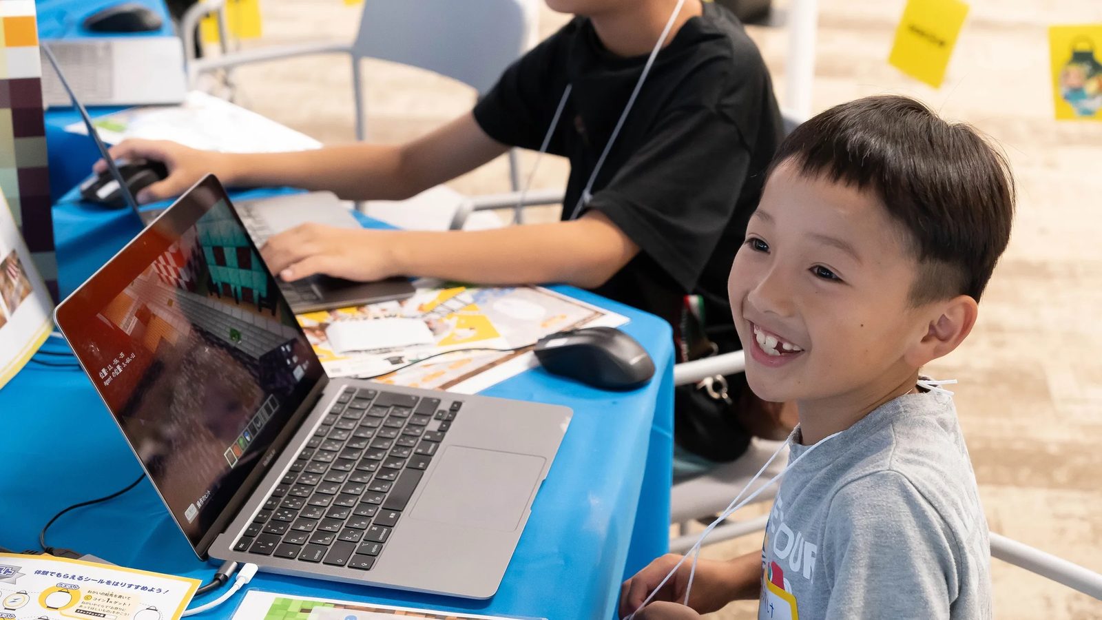 会場でノートPCの画面をのぞき込んで笑う男の子