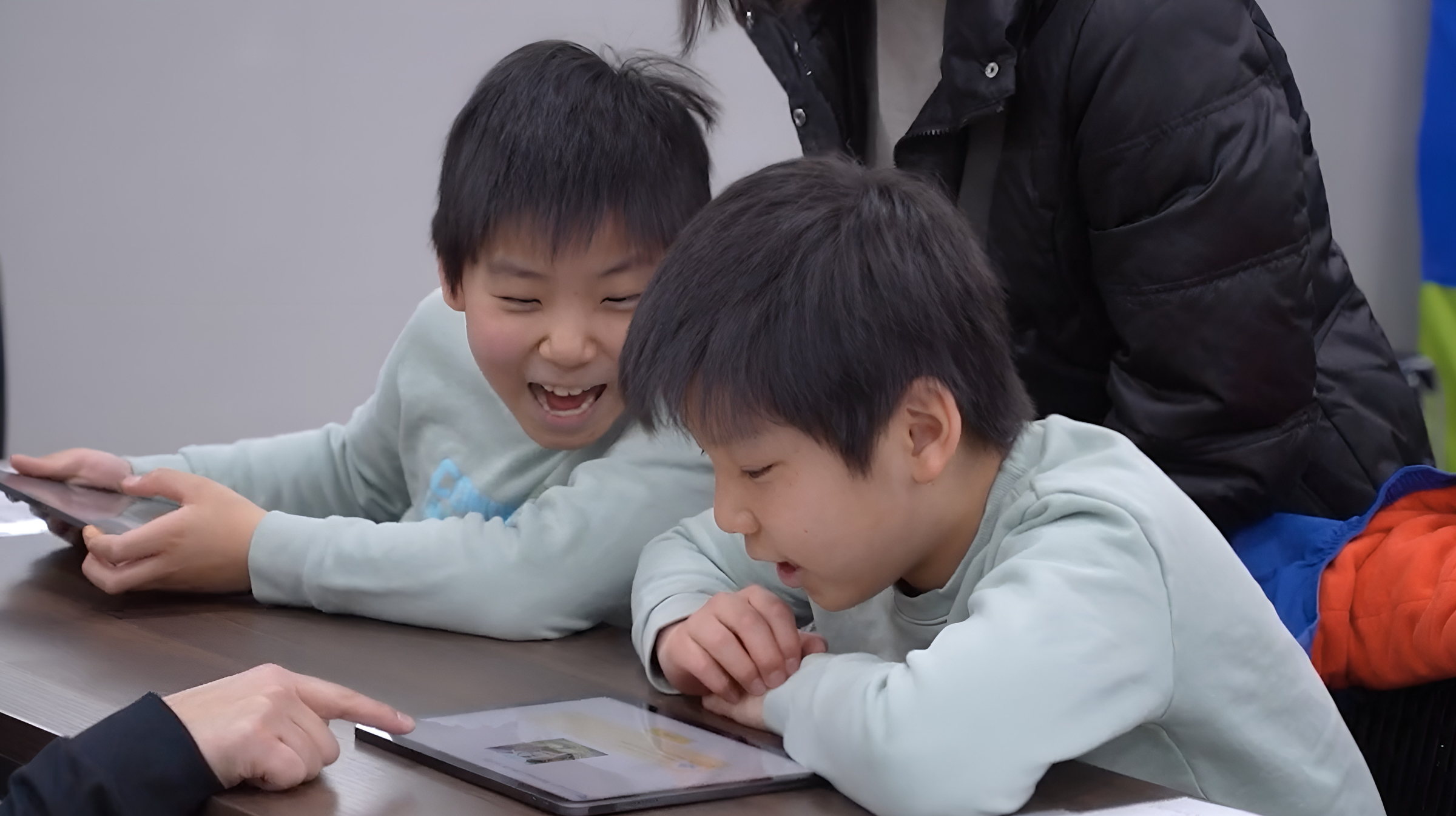SOZOWフェスの会場で、画面を見ながら声をあげて笑う2人の子ども